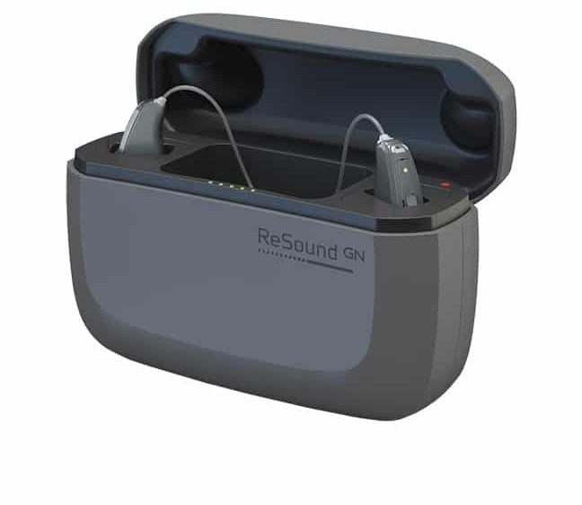 A set of hearing aids in a charging cradle