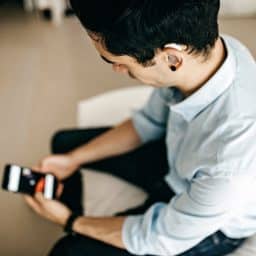 Young businessman with a hearing aid looking at his smartphone.